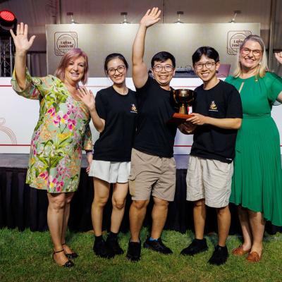Members of the Meeting Place team posing in front of the Kitchen stage with their Regional People's Choice Best Laksa award, with Minister Cahill and Minister Boothby