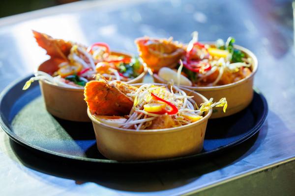 Three bowls of laksa sitting on a serving tray
